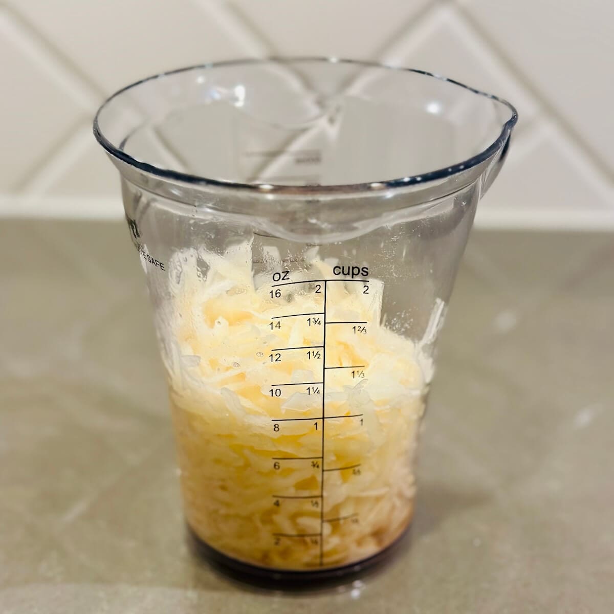 Grated potato in measuring cup